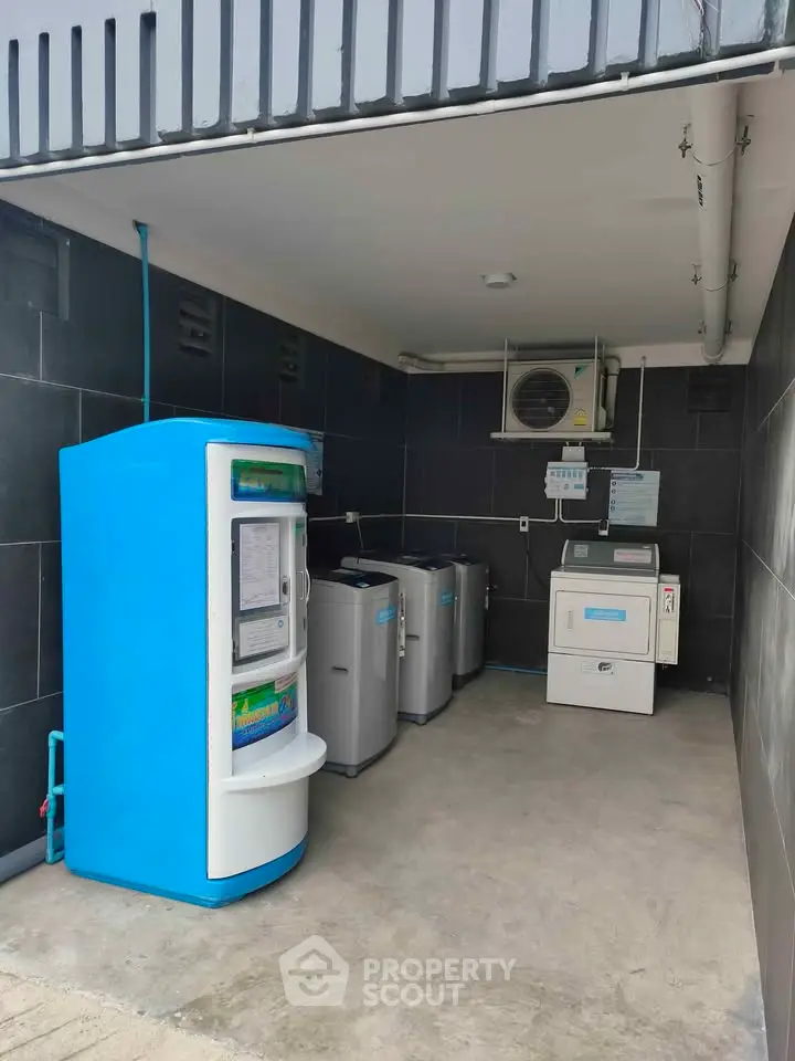Modern laundry area with washing machines and water dispenser in sleek tiled space.