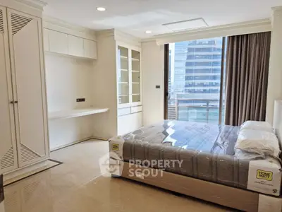 Spacious modern bedroom with large window and city view in luxury apartment.