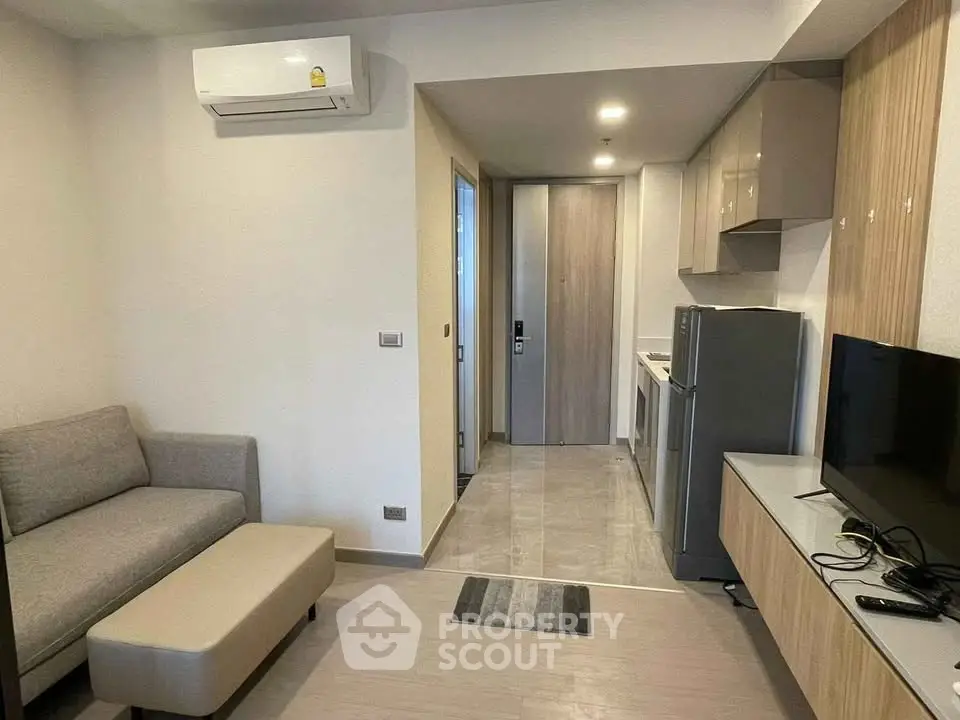 Modern compact living room with kitchenette, featuring sleek furniture and efficient layout.