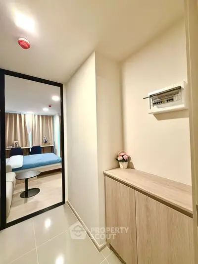 Modern apartment hallway leading to a cozy bedroom with stylish decor and natural light.