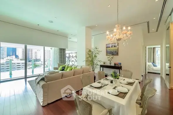 Luxurious open-plan living and dining area with elegant chandelier and city view.