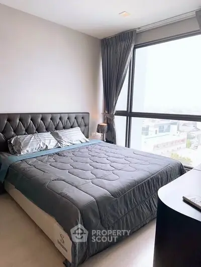 Modern bedroom with large window and stylish decor in a high-rise apartment.