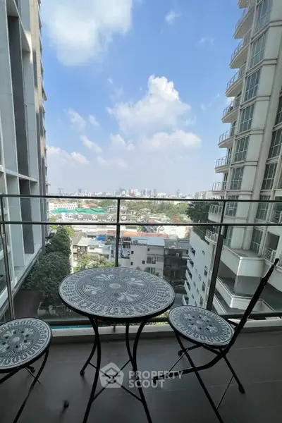 Stunning city view from a modern high-rise balcony with elegant outdoor seating.