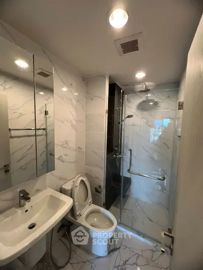 Modern bathroom with marble tiles, glass shower, and sleek fixtures.