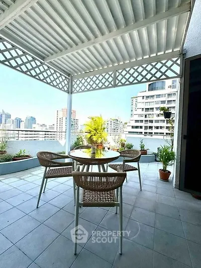 Spacious balcony with city view, featuring outdoor seating and lush greenery, perfect for relaxation and entertainment.