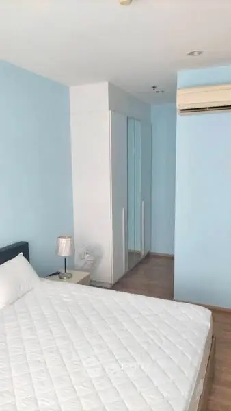 Cozy bedroom with blue walls, white wardrobe, and air conditioning unit.