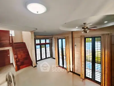 Spacious living room with large windows and modern ceiling fan