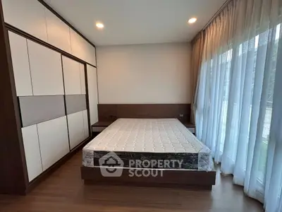 Spacious bedroom with large windows and modern design, featuring a comfortable bed and ample natural light.