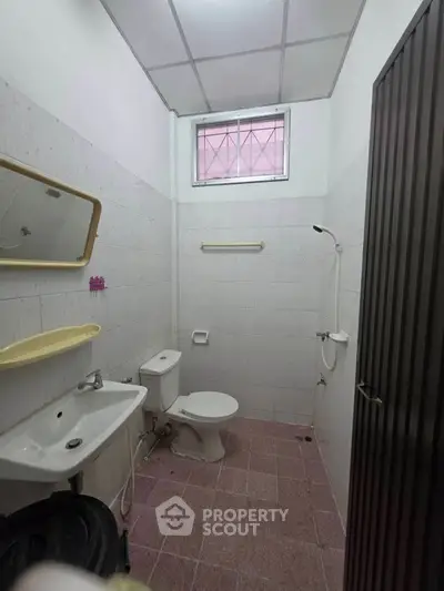 Compact bathroom with toilet, sink, and shower in a minimalist design.