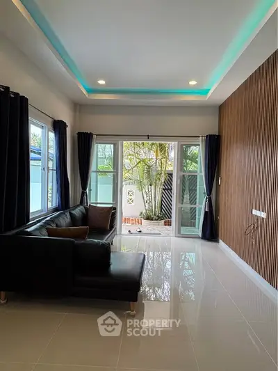 Modern living room with sleek design and large windows opening to a garden view.