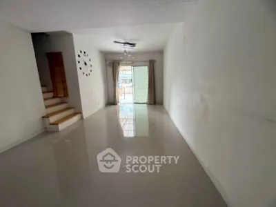 Spacious living room with modern staircase and large window for natural light.