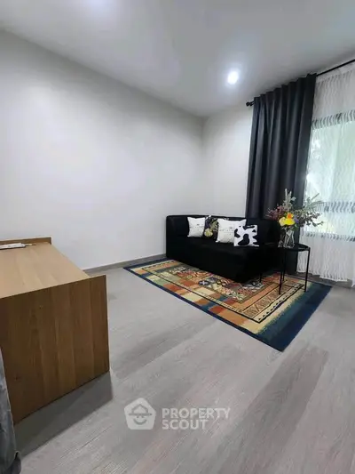 Modern living room with stylish sofa, elegant rug, and natural light from large window.