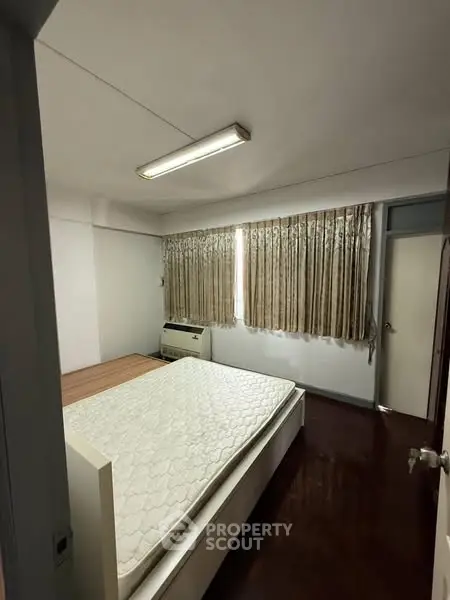 Cozy bedroom with natural light and wooden flooring, featuring a comfortable bed and air conditioning.