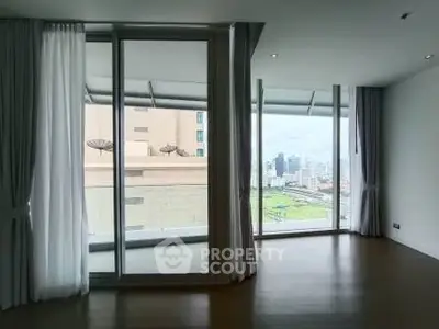 Spacious modern living room with floor-to-ceiling windows and city view balcony.