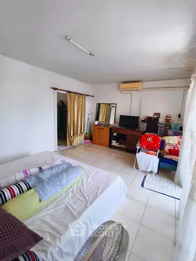 Spacious bedroom with natural light, featuring a cozy bed, dresser, and air conditioning unit.