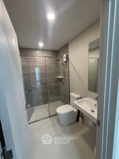 Modern bathroom with glass shower and sleek fixtures in contemporary apartment.