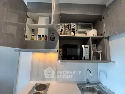 Modern kitchen with sleek cabinets, microwave, and stainless steel sink, perfect for urban living.