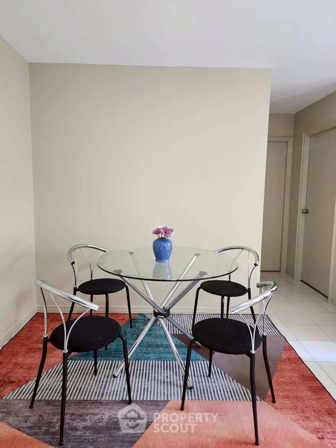 Modern dining area with glass table and stylish chairs on colorful rug