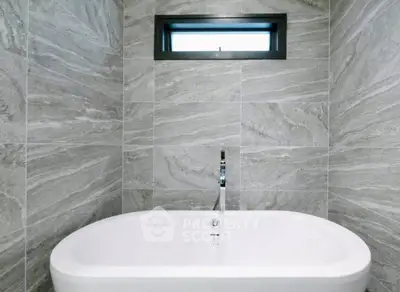 Luxurious bathroom with modern freestanding bathtub and elegant gray tile design.
