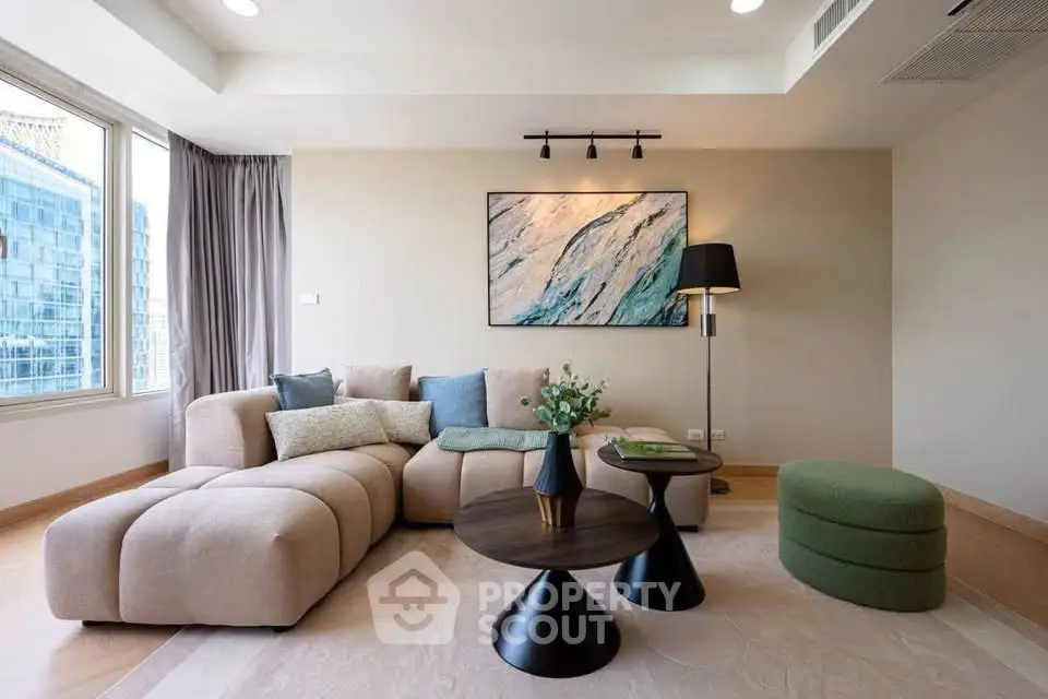 Modern living room with stylish furniture and large windows offering city views.