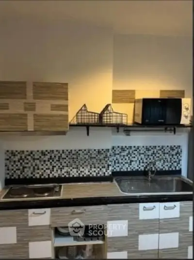 Modern kitchen with stylish backsplash and microwave, featuring sleek cabinetry and dual sink.