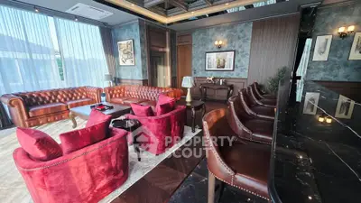Luxurious living room with elegant leather sofas and plush red chairs, perfect for sophisticated gatherings.