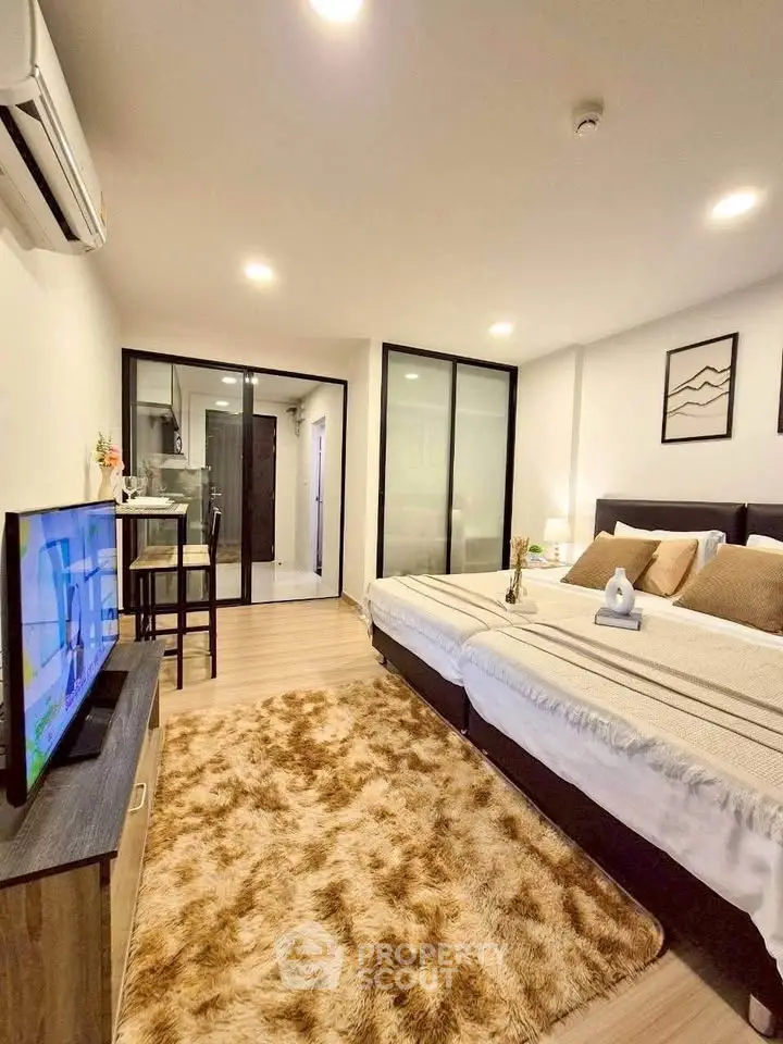 Modern bedroom with cozy decor and open layout leading to kitchen area.