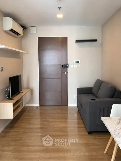 Modern living room with wooden flooring, sleek furniture, and air conditioning in a cozy apartment.