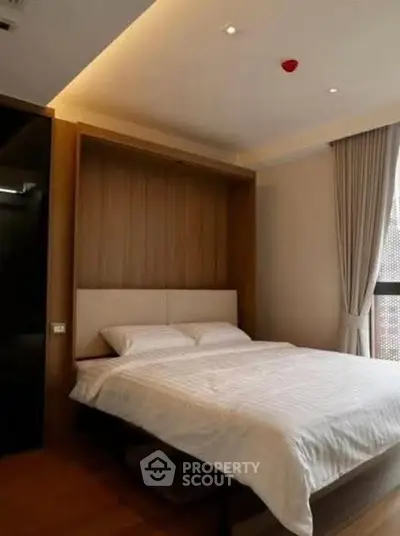 Modern bedroom with cozy lighting and large window for natural light.