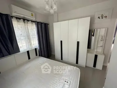 Modern bedroom with sleek white furniture and ample natural light