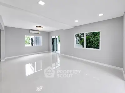 Spacious modern living room with large windows and glossy white tiles