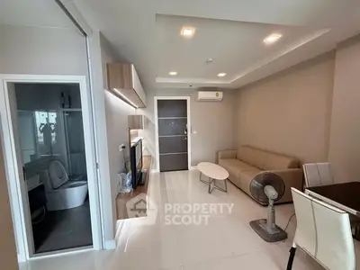 Modern living room with beige sofa, wall-mounted shelves, and adjacent bathroom