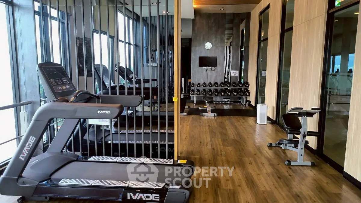 Modern gym with state-of-the-art equipment and sleek wooden flooring in a luxury residential building.