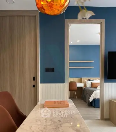 Modern interior with open layout, featuring a stylish living area and a glimpse into a cozy bedroom.