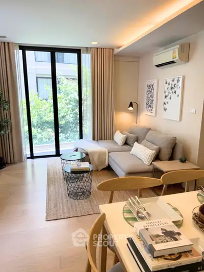 Modern living room with cozy sofa, stylish decor, and large windows overlooking greenery.