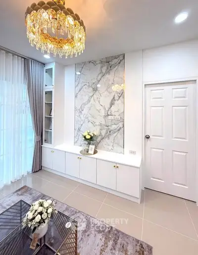 Elegant living room with chandelier and marble accent wall, featuring modern decor and natural light.