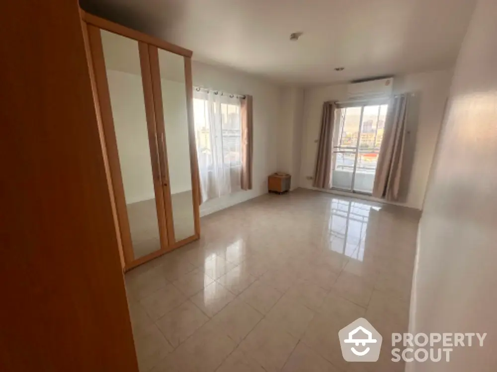 Spacious empty bedroom with mirrored wardrobe and balcony access