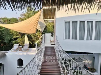 Stunning tropical villa with rope bridge and sunlit terrace, perfect for relaxation.