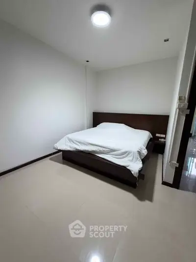 Spacious minimalist bedroom with modern bed and sleek flooring, perfect for restful nights.