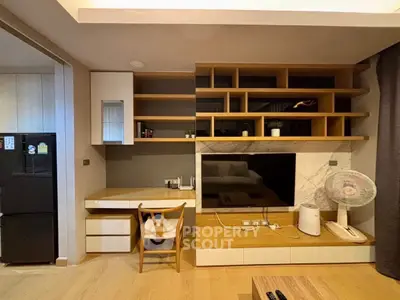 Modern living room with built-in shelves and TV, featuring stylish furniture and decor.