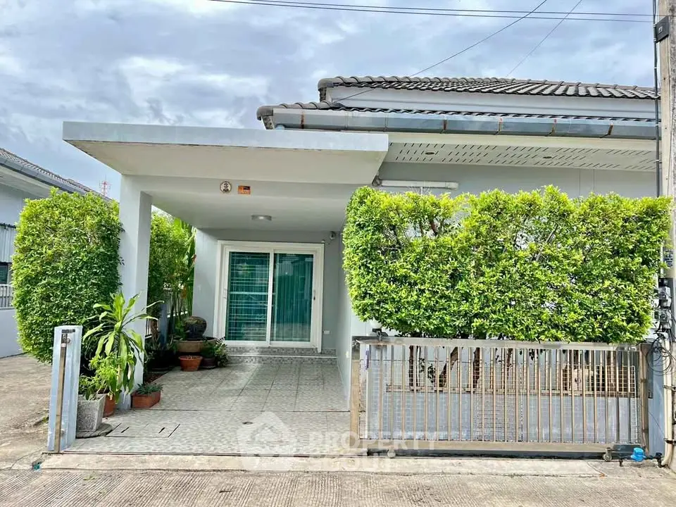 Charming suburban home with lush greenery and gated entrance.
