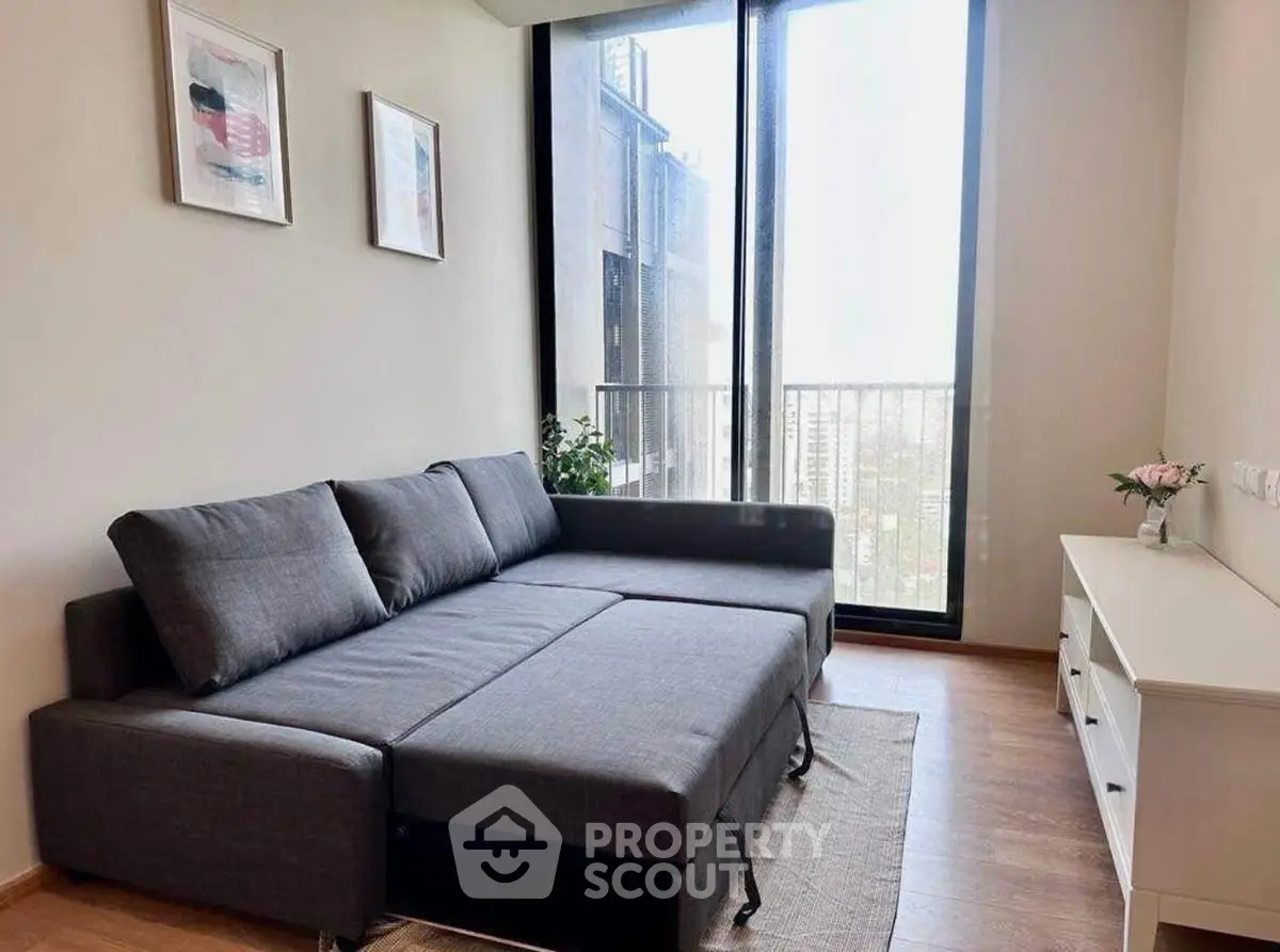 Modern living room with stylish gray sofa and large windows offering natural light.