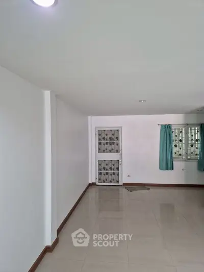 Spacious empty room with tiled flooring and natural light