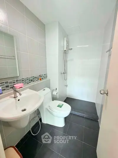 Modern bathroom with sleek design, featuring a shower, toilet, and sink in a compact layout.