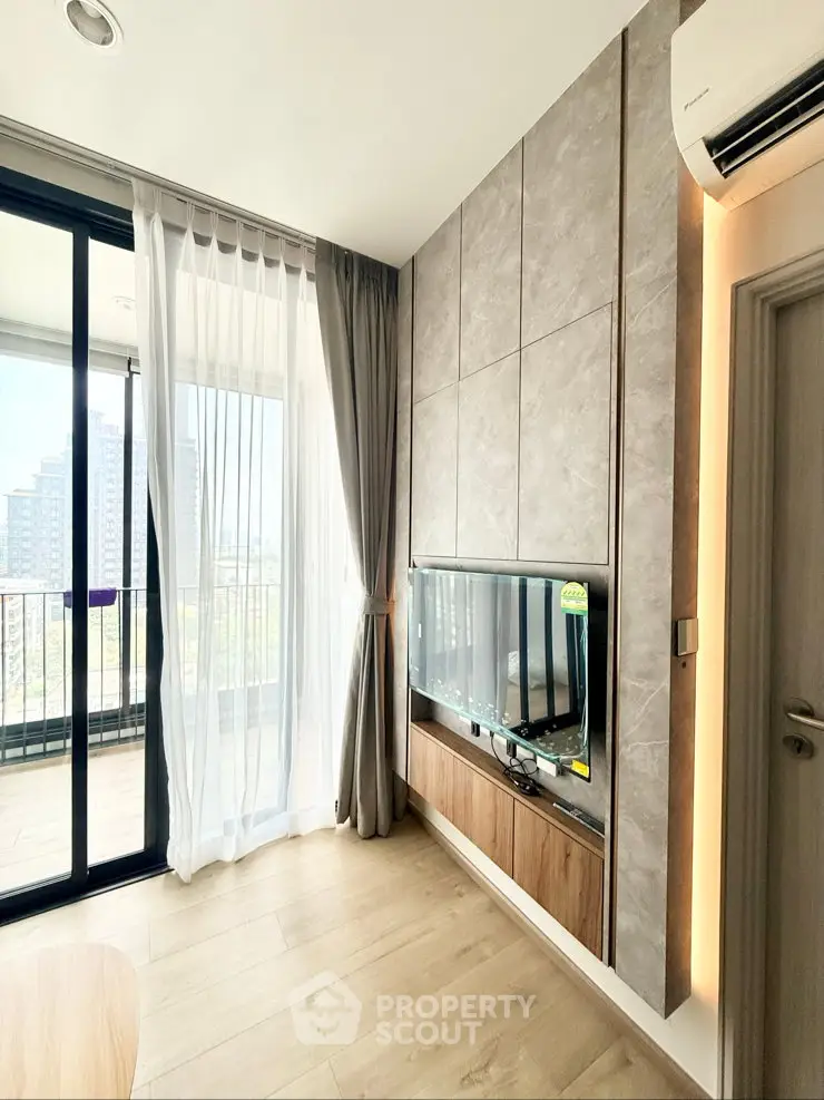 Modern living room with large windows and balcony view in a high-rise apartment.