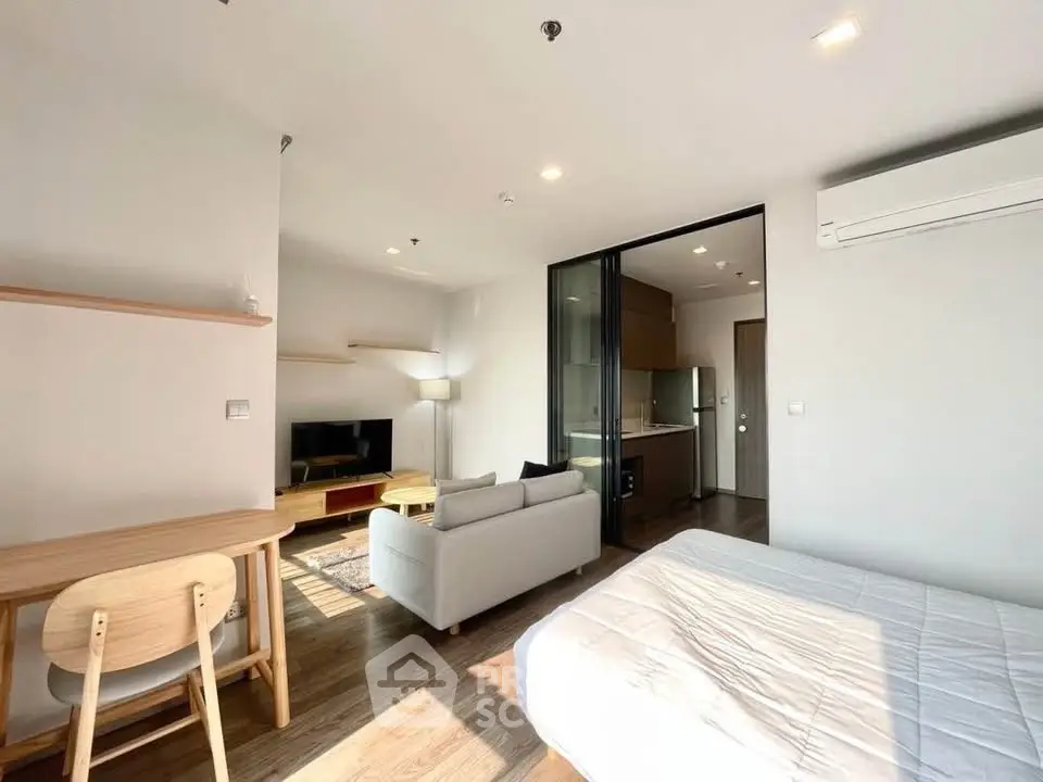 Modern studio apartment with open layout, featuring a cozy living area, compact kitchen, and bright natural lighting.