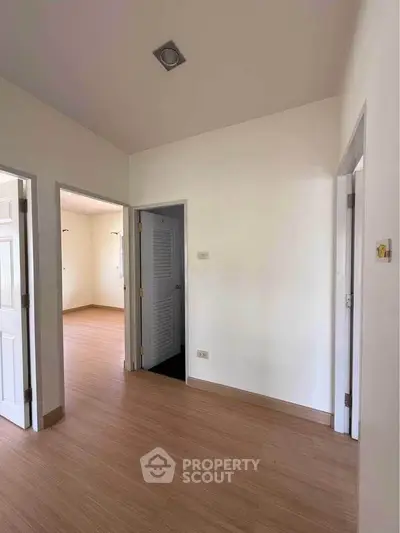 Spacious interior with wooden flooring and multiple doorways, ideal for versatile living arrangements.