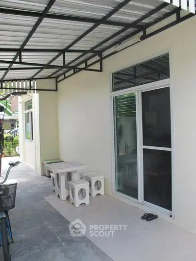 Charming outdoor patio with modern seating and sliding glass door, perfect for relaxation.