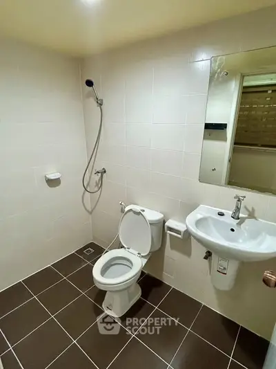 Modern bathroom with shower, toilet, and sink in a tiled setting.