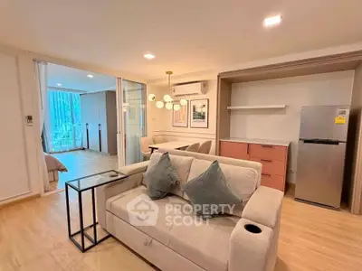 Modern living room with open layout and stylish decor, featuring a cozy sofa and sleek kitchen area.